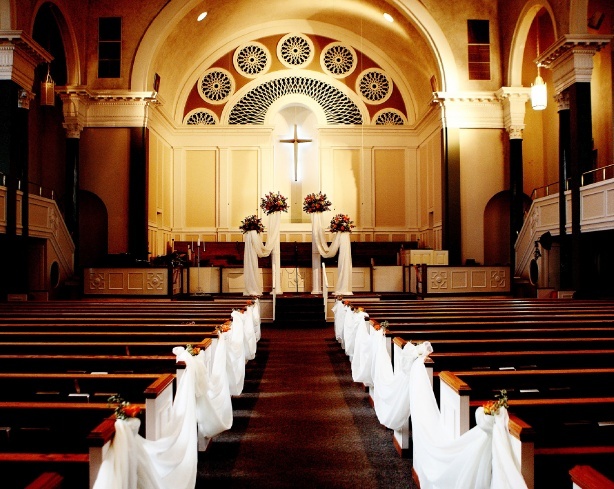 Białe wstęgi w alejce ślubnej jako dekoracja kościoła na ślub